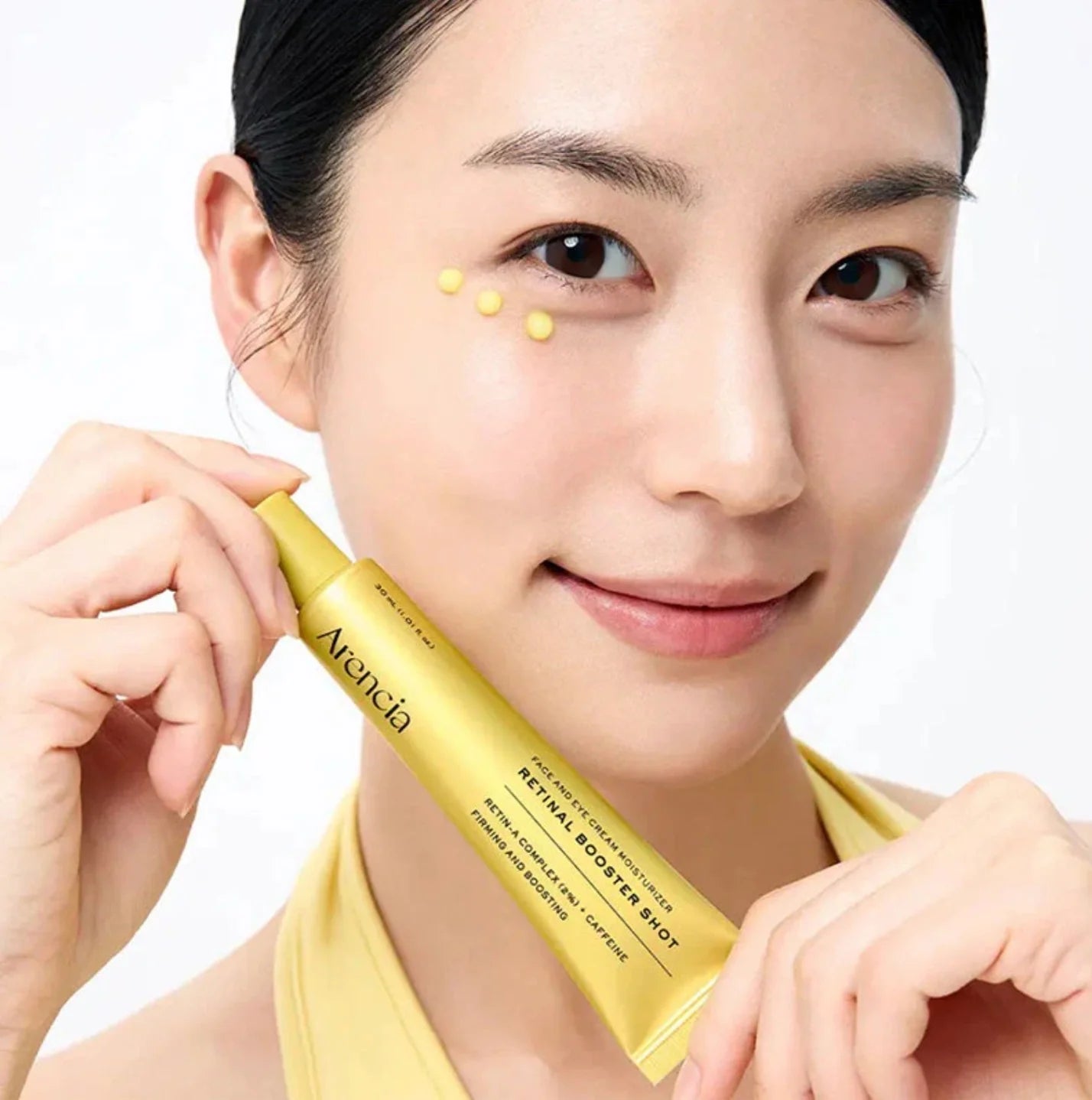 Woman holding a yellow skincare product with 'Avencia' branding on a white background