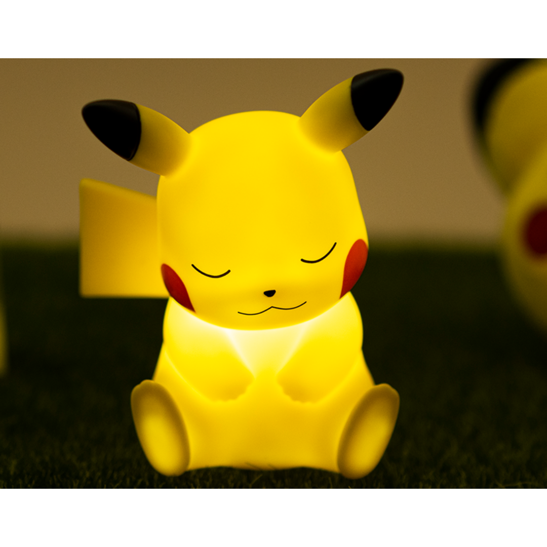Charming sleeping Pikachu LED night light glowing in warm yellow on a grassy surface, creating a soothing atmosphere for bedrooms, nurseries, or Pokémon-themed decor.