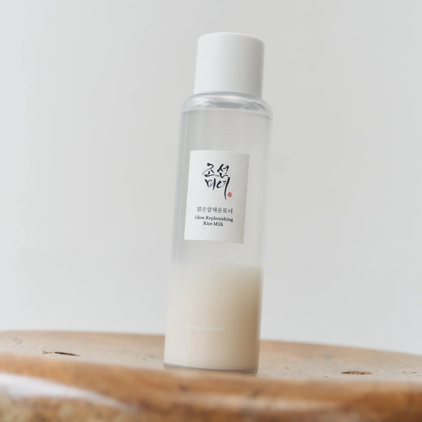 White bottle with a label on a wooden surface against a white background