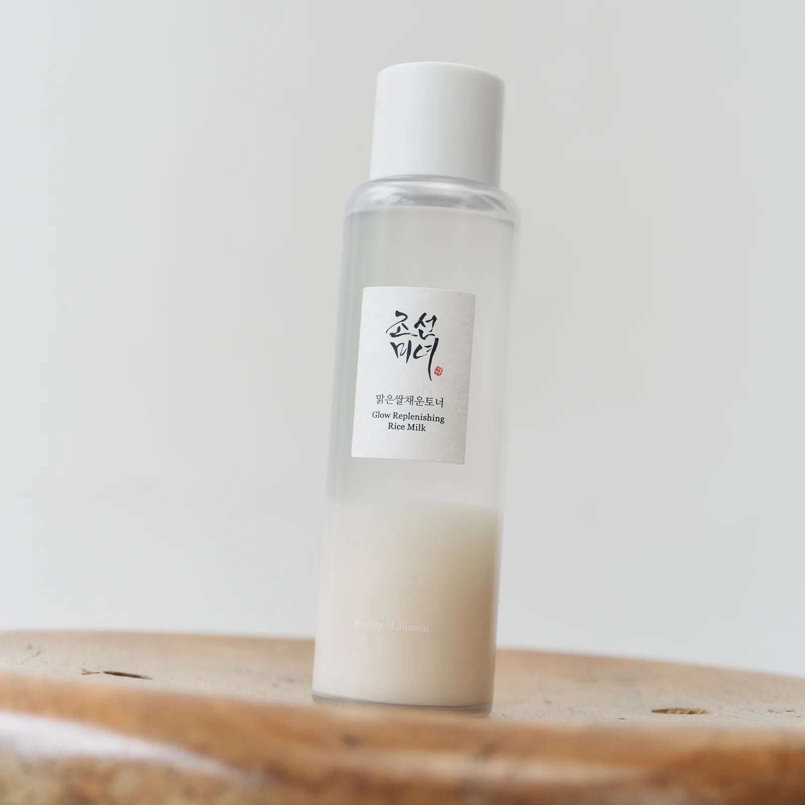 White bottle with a label on a wooden surface against a white background