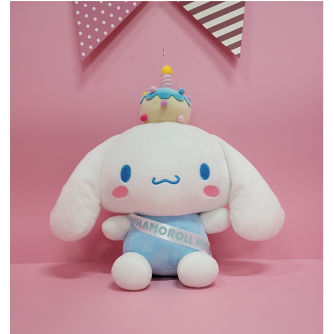 Cute Cinnamoroll plush toy with a birthday cupcake crown and “Cinnamoroll Happy Birth Day” sash, sitting against a pastel pink background – perfect for kawaii lovers and Sanrio collectors.