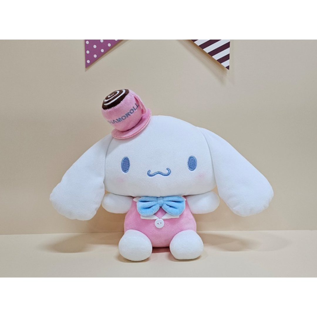 Cinnamoroll plush wearing a pink cafe-style outfit with a mini roll cake hat and blue bowtie, a must-have for dessert-themed plush toy collectors.