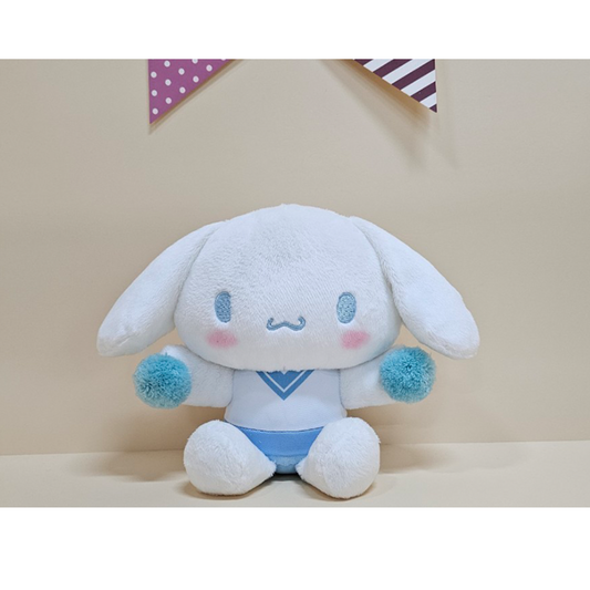 Charming Cinnamoroll plush in a blue cheer outfit with fuzzy pom-poms, perfect for team spirit and cuteness.