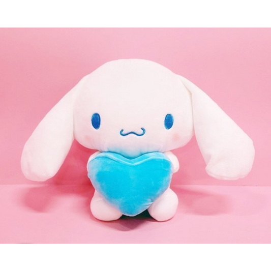 “Cinnamoroll plush toy holding a blue heart pillow – soft white Sanrio bunny with long ears, perfect for kawaii lovers and pastel-themed decor.”