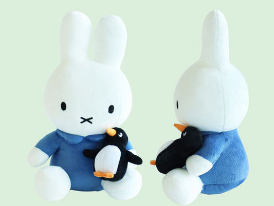 Miffy white bunny plush in a blue outfit holding a small black and white penguin plush – soft cuddly toy from the Miffy character collection