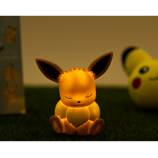 Adorable sleeping Eevee Pokémon LED night light glowing in soft amber, resting on a grassy surface with a warm, cozy nighttime atmosphere – perfect for children's rooms, gifts, and Pokémon lovers.