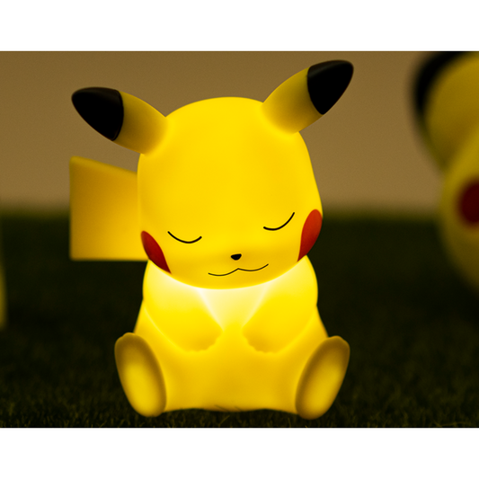 Charming sleeping Pikachu LED night light glowing in warm yellow on a grassy surface, creating a soothing atmosphere for bedrooms, nurseries, or Pokémon-themed decor.