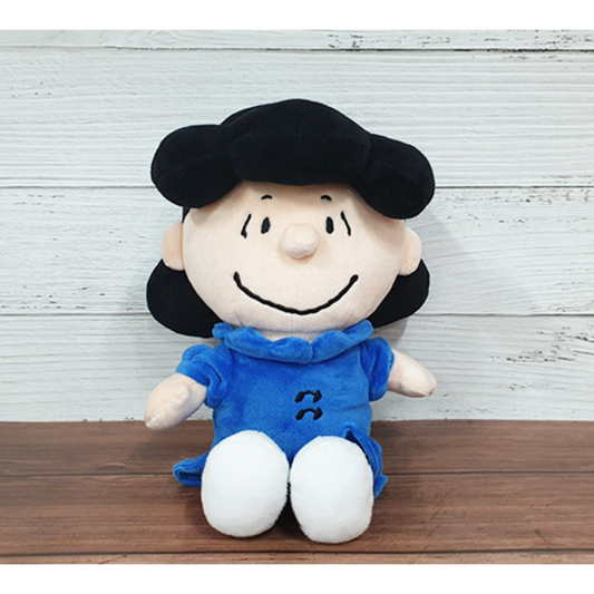 Lucy van Pelt plush doll from Peanuts, wearing a blue dress and white shoes, sitting against a wood-textured background — ideal collectible gift for Peanuts fans and kids.